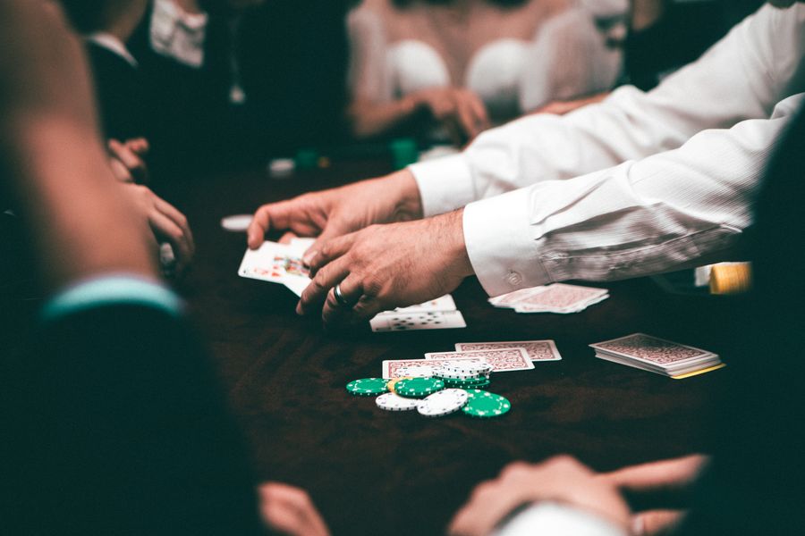 Kartu remi dan keping poker tersusun di atas meja hijau