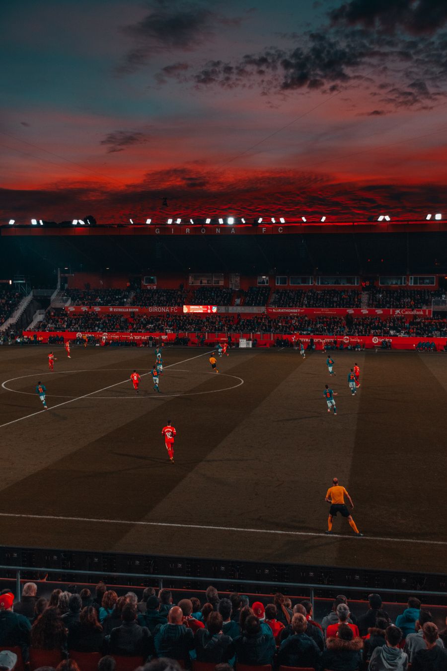 Stadion sepak bola dengan lampu sorot menyala pada malam pertandingan